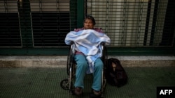 Un paciente con tratamiento de diálisis espera frente a una clínica cerrada tras un nuevo apagón este martes en Caracas.