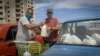 Dos hombres acomodan la mercancía adquirida en una de las tiendas en dólares abiertas la semana pasada en Cuba. (Adalberto Roque / AFP)