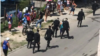 Foto Archivo. Boinas negras caminan junto a personas que permanecen en una cola.
