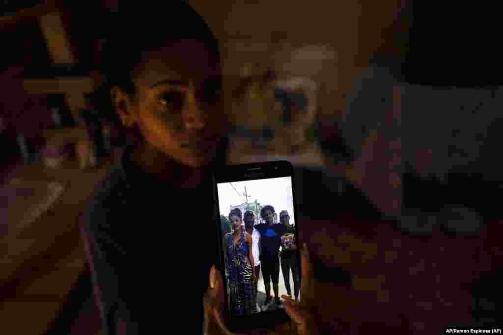 María Carla Milán Ramos muestra una foto en su teléfono de su esposo con sus hermanos, detenidos por participar el 11 de julio.